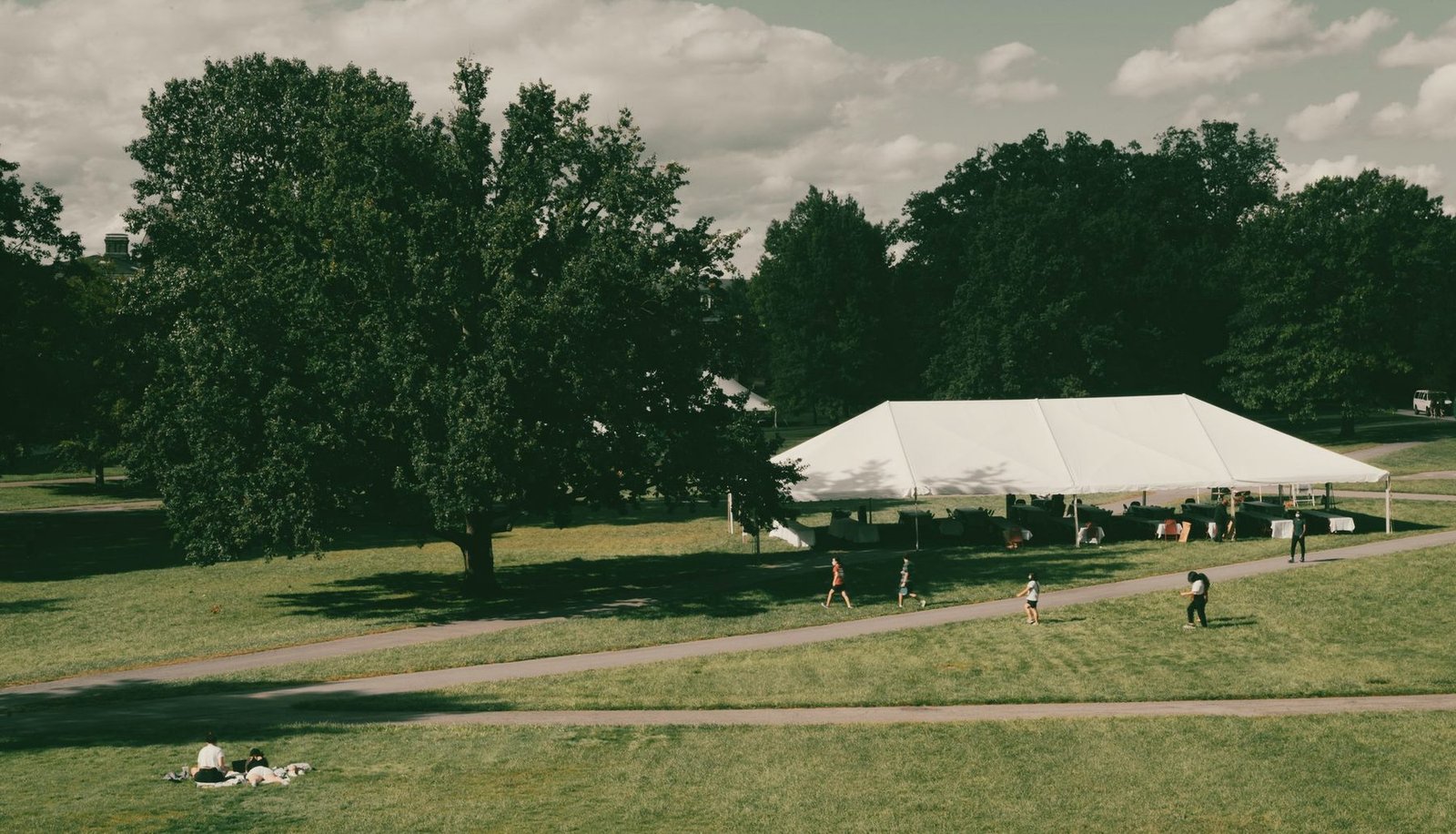 White event marquee standing in an open field with trees behind it.