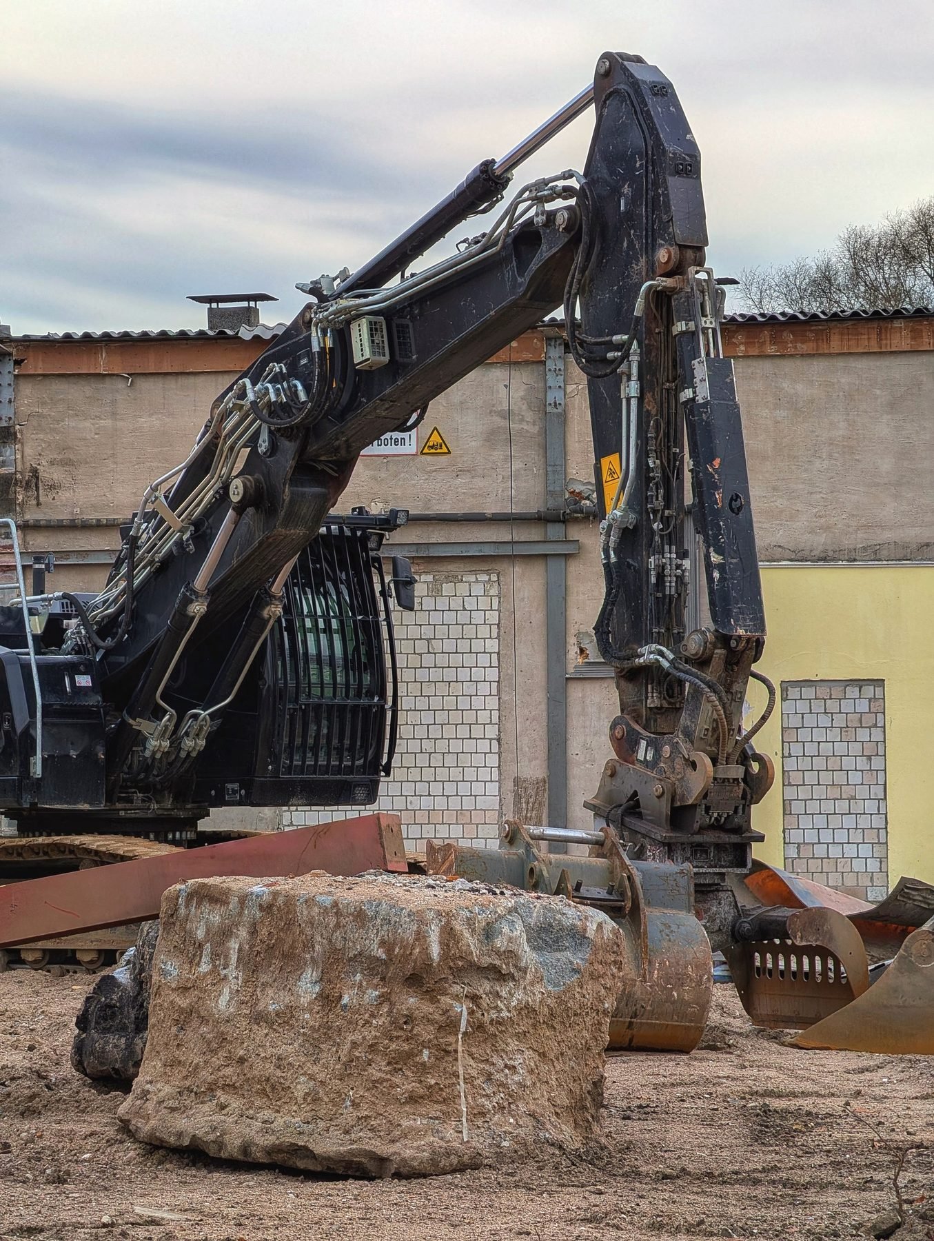 Excavator bucket gripping a large boulder on a worksite.