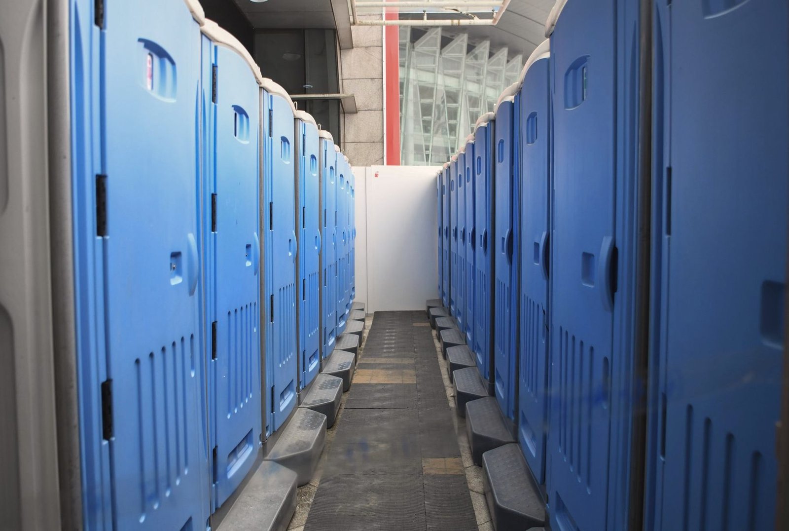 Close view down a row of blue portable restroom units.